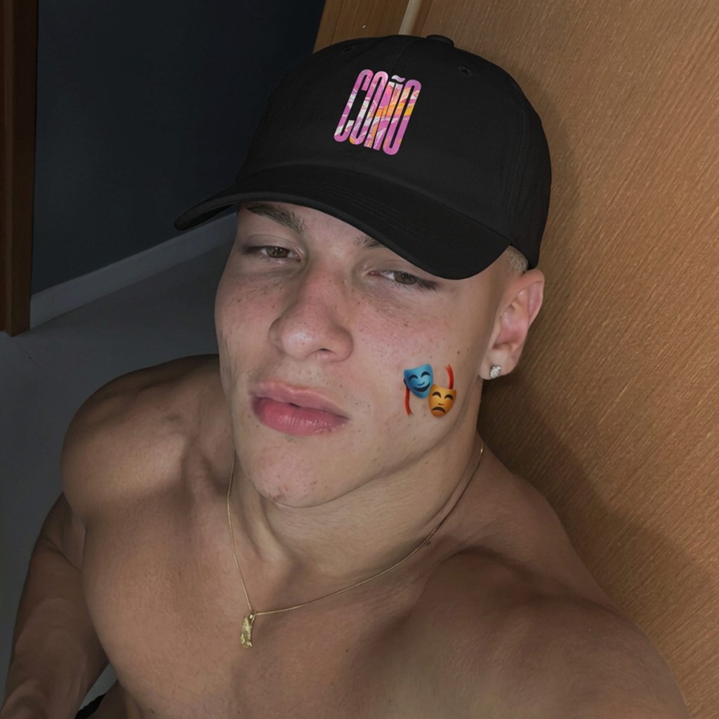 Smiling model in black Gayer Things Coño dad cap — front-facing portrait, marble COÑO typography