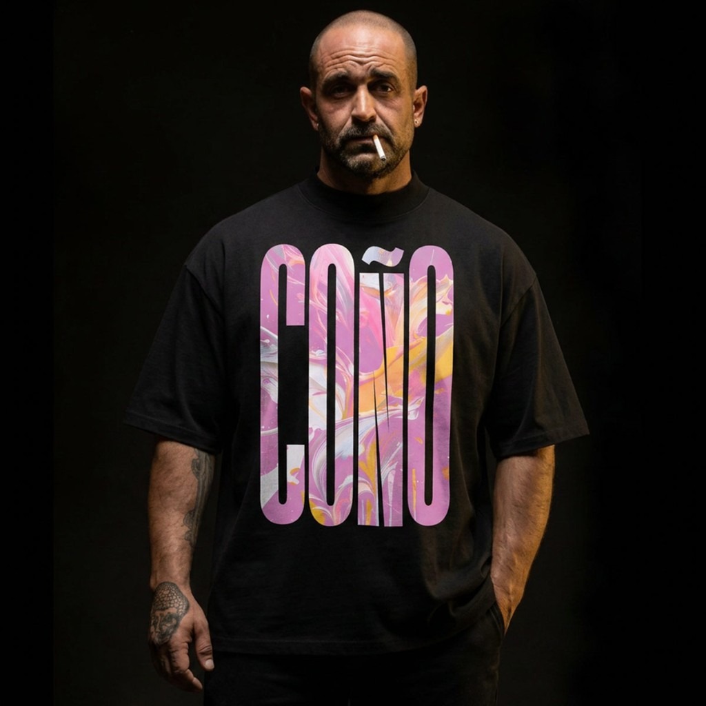 Black Gayer Things Coño organic oversized tee on dark studio backdrop — model in vertical marble-pour COÑO lettering